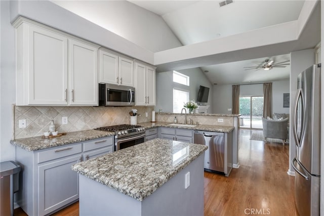 2925 E El Paso Ave, Fresno, CA 93720 - kitchen featuring stainless steel appliances, vaulted ceiling, a peninsula, light wood-style floors, and backsplash