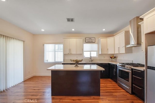 7820 Fulton Ave, North Hollywood, CA 91605 - kitchen with stainless steel appliances, wall chimney range hood, light countertops, a kitchen island, and white cabinetry