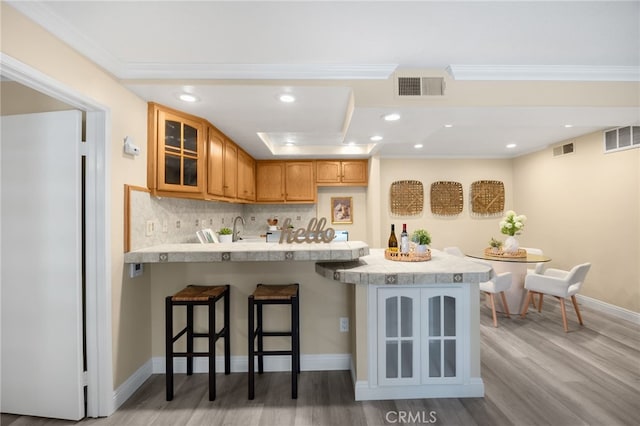 3020 Associated Rd Unit 110, Fullerton, CA 92835 - kitchen featuring a peninsula, glass insert cabinets, light wood-type flooring, light countertops, and a breakfast bar