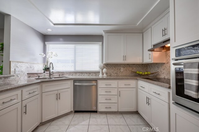 1354 Shadow Ln Unit 102, Fullerton, CA 92831 - kitchen featuring appliances with stainless steel finishes, under cabinet range hood, tasteful backsplash, and white cabinetry