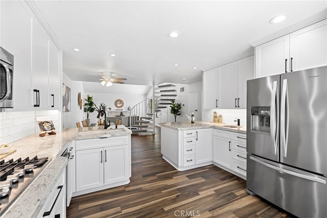 18714 Maplewood Cir, Huntington Beach, CA 92646 - kitchen with stainless steel appliances, a peninsula, dark wood-style flooring, white cabinets, and backsplash