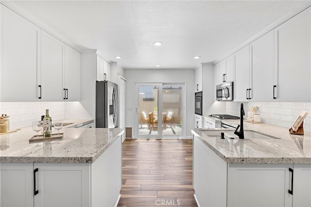 18714 Maplewood Cir, Huntington Beach, CA 92646 - kitchen featuring appliances with stainless steel finishes, white cabinets, light stone counters, dark wood-type flooring, and recessed lighting