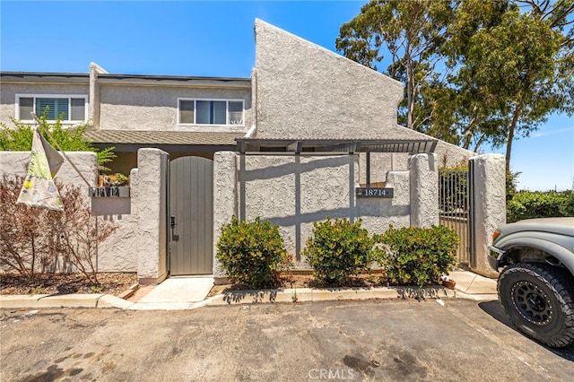 18714 Maplewood Cir, Huntington Beach, CA 92646 - view of property with a gate, stucco siding, and uncovered parking