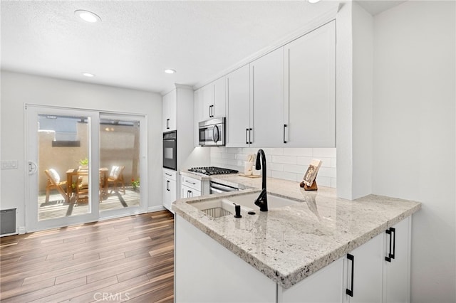18714 Maplewood Cir, Huntington Beach, CA 92646 - kitchen featuring appliances with stainless steel finishes, wood finished floors, decorative backsplash, white cabinetry, and light stone counters