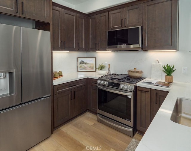 402 W Grand Ave Unit 104, Grover Beach, CA 93433 - kitchen featuring appliances with stainless steel finishes, light countertops, dark brown cabinets, and light wood-style flooring