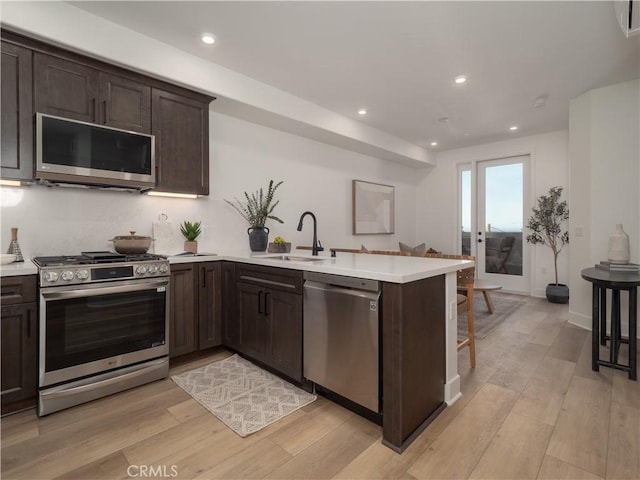 402 W Grand Ave Unit 104, Grover Beach, CA 93433 - kitchen featuring appliances with stainless steel finishes, a peninsula, dark brown cabinets, light countertops, and recessed lighting