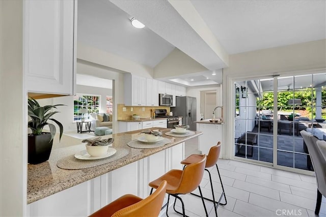 124 Marion Blvd, Fullerton, CA 92835 - kitchen featuring stainless steel appliances, white cabinetry, a kitchen bar, light tile patterned flooring, and lofted ceiling
