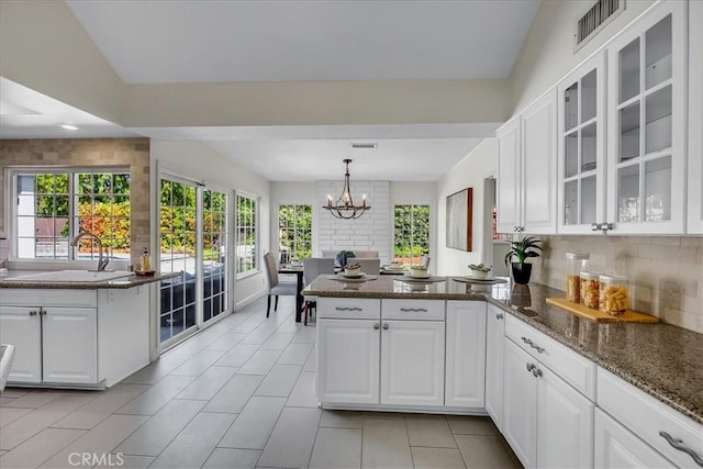 124 Marion Blvd, Fullerton, CA 92835 - kitchen with a peninsula, white cabinetry, glass insert cabinets, and a chandelier