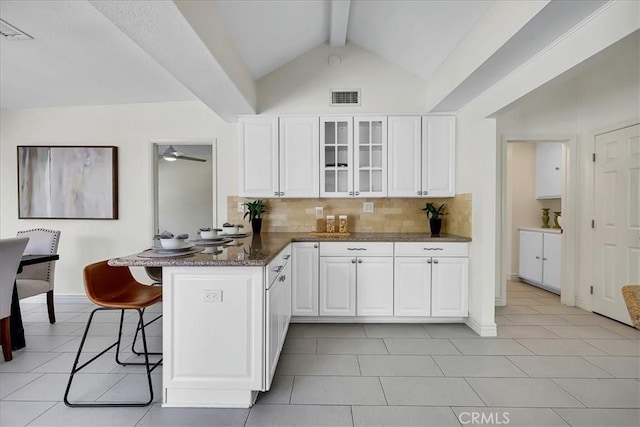 124 Marion Blvd, Fullerton, CA 92835 - kitchen with a peninsula, backsplash, glass insert cabinets, a kitchen breakfast bar, and white cabinetry