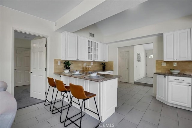 124 Marion Blvd, Fullerton, CA 92835 - kitchen featuring glass insert cabinets, tasteful backsplash, a breakfast bar, white cabinetry, and a peninsula