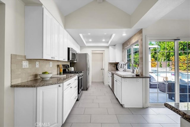124 Marion Blvd, Fullerton, CA 92835 - kitchen featuring stainless steel appliances, tasteful backsplash, white cabinetry, dark stone counters, and vaulted ceiling