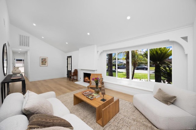 11741 Foster Rd, Los Alamitos, CA 90720 - living area featuring light wood-style flooring, recessed lighting, high vaulted ceiling, and a lit fireplace