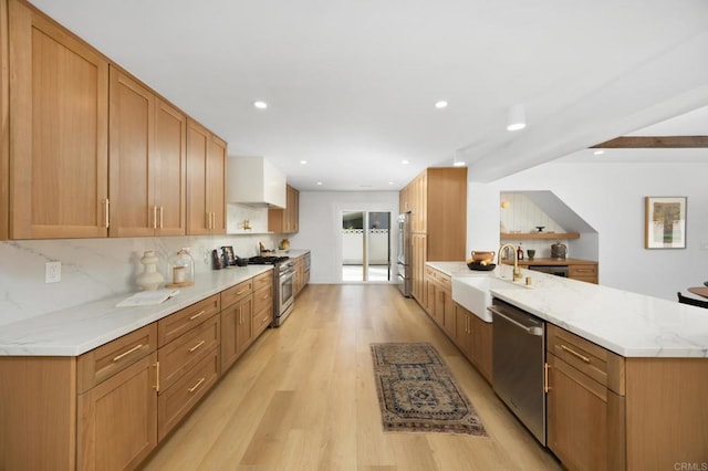 11741 Foster Rd, Los Alamitos, CA 90720 - kitchen with premium appliances, a peninsula, light wood-type flooring, decorative backsplash, and light stone countertops