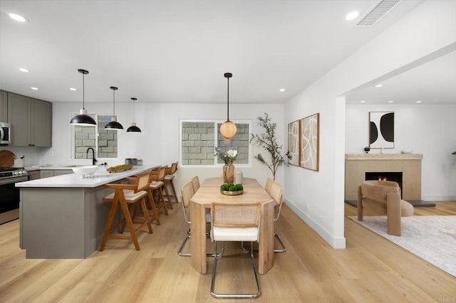 19222 S Grandee Ave, Carson, CA 90746 - dining area with light wood-type flooring, a warm lit fireplace, and recessed lighting