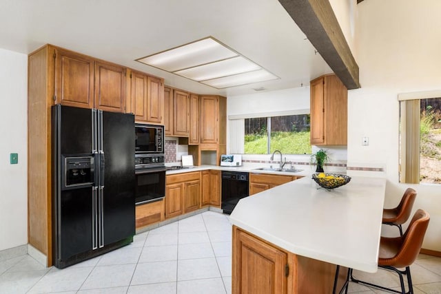 10665 Loire Ave, San Diego, CA 92131 - kitchen with black appliances, a peninsula, tasteful backsplash, a kitchen breakfast bar, and light tile patterned floors
