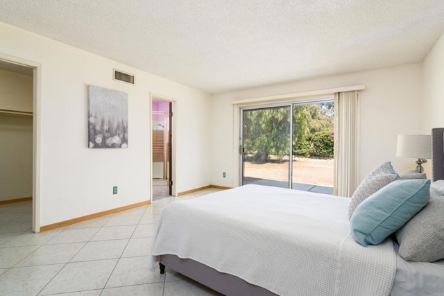 10665 Loire Ave, San Diego, CA 92131 - bedroom with access to outside, a textured ceiling, a spacious closet, light tile patterned flooring, and connected bathroom