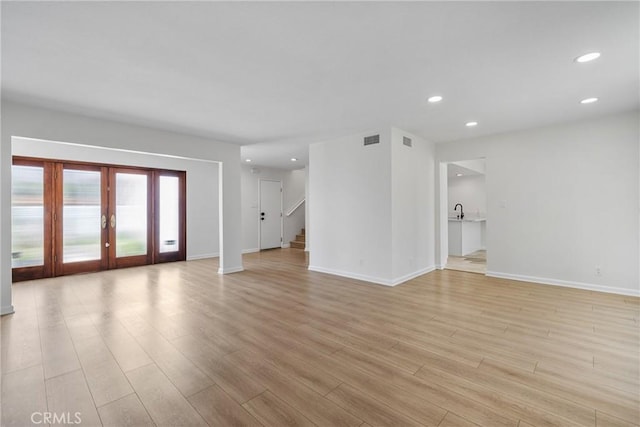 20 Mayapple Way, Irvine, CA 92612 - unfurnished living room with light wood-type flooring, french doors, recessed lighting, and stairs
