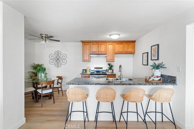 21951 Rimhurst Dr Unit F201, Lake Forest, CA 92630 - kitchen featuring electric stove, under cabinet range hood, a peninsula, a ceiling fan, and a kitchen breakfast bar
