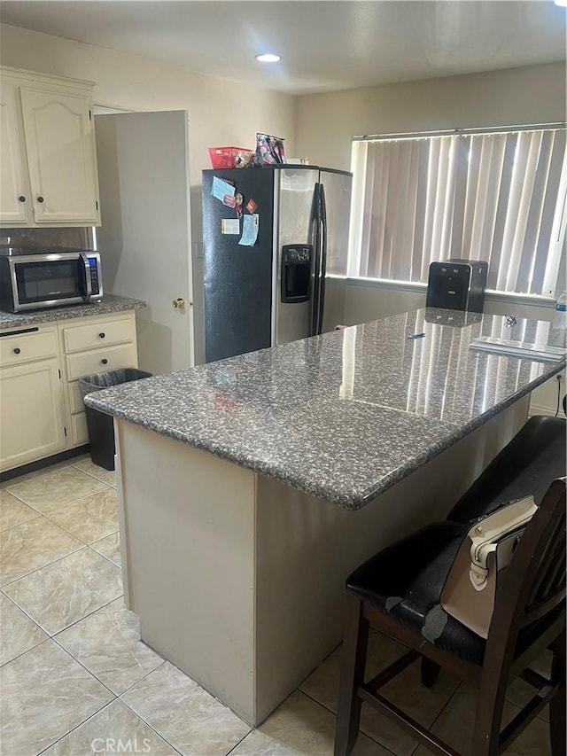 26832 6th St, Highland, CA 92346 - kitchen featuring stainless steel appliances, a breakfast bar, dark stone counters, and white cabinetry