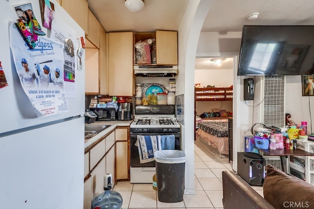 1270 S Hicks Ave, Los Angeles, CA 90023 - kitchen featuring freestanding refrigerator, gas stove, under cabinet range hood, light tile patterned floors, and arched walkways