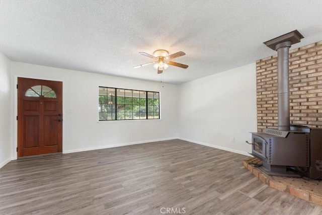 21999 Riverside Ave, Red Bluff, CA 96080 - unfurnished living room with wood finished floors, a textured ceiling, a ceiling fan, and a wood stove