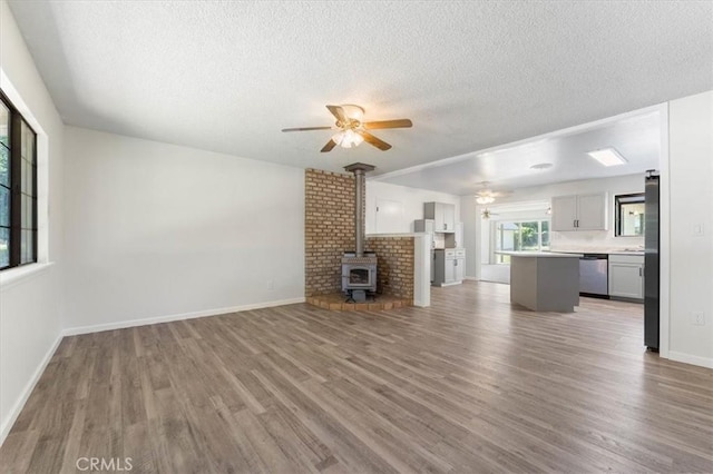 21999 Riverside Ave, Red Bluff, CA 96080 - unfurnished living room with a ceiling fan, wood finished floors, a wood stove, and a textured ceiling