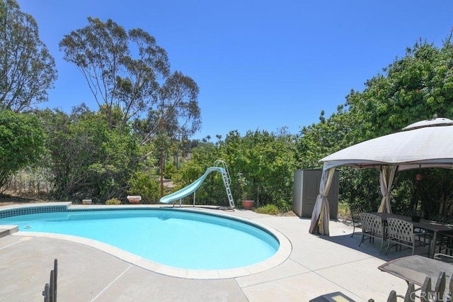 3096 Coral Tree Ln, Fallbrook, CA 92028 - swimming pool with a gazebo, a water slide, a patio area, view of scattered trees, and outdoor dining space