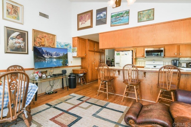 3096 Coral Tree Ln, Fallbrook, CA 92028 - kitchen with stainless steel microwave, white fridge with ice dispenser, a high ceiling, range, and brown cabinets