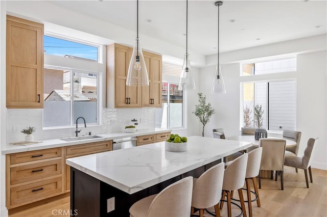 2102 Marshallfield Ln Unit A, Redondo Beach, CA 90278 - kitchen featuring light wood-type flooring, a kitchen breakfast bar, decorative backsplash, light stone countertops, and light brown cabinets