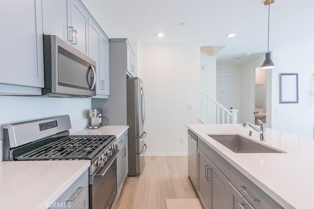 27474 Quiet View Pl, Valencia, CA 91381 - kitchen with appliances with stainless steel finishes, gray cabinetry, light countertops, light wood-style floors, and decorative light fixtures