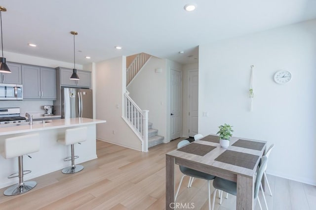 27474 Quiet View Pl, Valencia, CA 91381 - kitchen with appliances with stainless steel finishes, gray cabinetry, light wood-type flooring, light countertops, and a kitchen bar