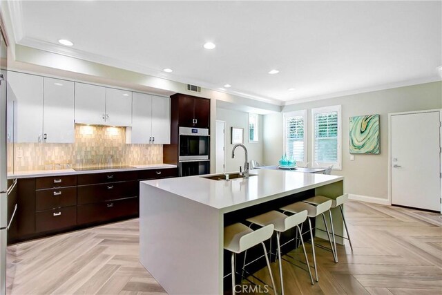 3090 Mangular Ave, Corona, CA 92882 - kitchen featuring double oven, crown molding, a kitchen bar, light countertops, and dark brown cabinets