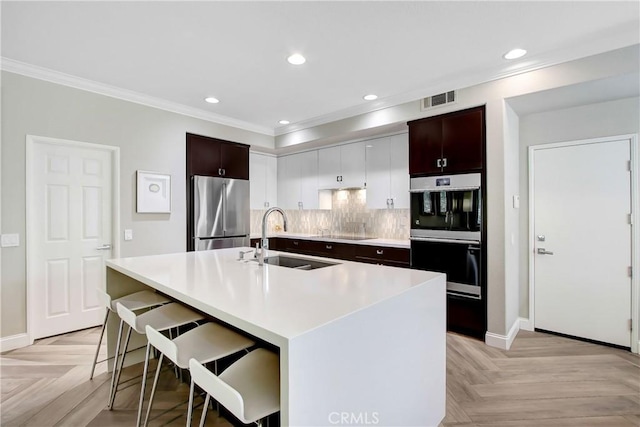 3090 Mangular Ave, Corona, CA 92882 - kitchen with stainless steel appliances, crown molding, a kitchen island with sink, decorative backsplash, and light countertops