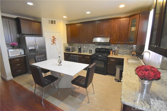 13647 Mesa Linda Ave, Victorville, CA 92392 - kitchen with black gas range, range hood, white microwave, stainless steel fridge, and backsplash