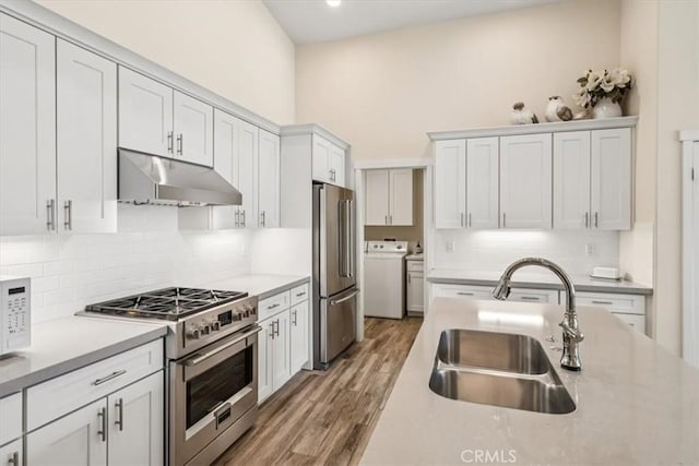 232 Loretta Way, Calimesa, CA 92320 - kitchen featuring appliances with stainless steel finishes, under cabinet range hood, washer / clothes dryer, decorative backsplash, and light countertops