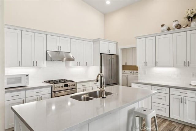 232 Loretta Way, Calimesa, CA 92320 - kitchen with appliances with stainless steel finishes, independent washer and dryer, under cabinet range hood, an island with sink, and tasteful backsplash