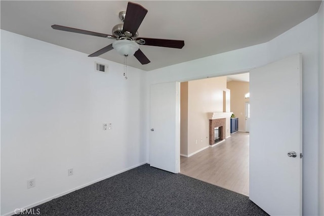 28076 Orangegrove Ave, Menifee, CA 92584 - spare room featuring a ceiling fan, dark carpet, and a fireplace