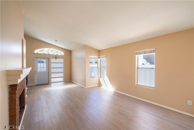28076 Orangegrove Ave, Menifee, CA 92584 - unfurnished living room with wood finished floors, vaulted ceiling, and a brick fireplace