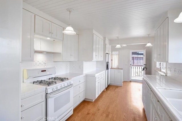 625 High Dr, Laguna Beach, CA 92651 - kitchen featuring white appliances, light wood-style flooring, tile countertops, backsplash, and white cabinetry