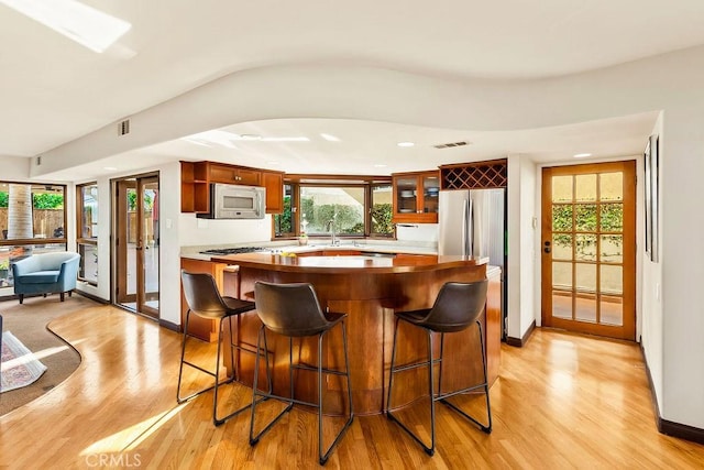 34283 Via Lopez, Dana Point, CA 92624 - kitchen with white microwave, light wood finished floors, a breakfast bar area, glass insert cabinets, and recessed lighting