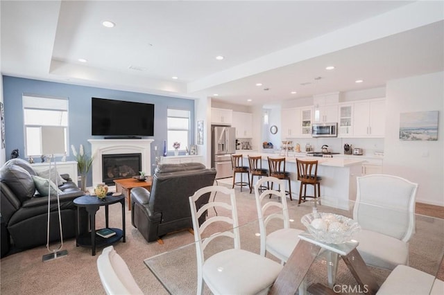 32096 Hyacinth Way, Temecula, CA 92591 - living room featuring plenty of natural light, light carpet, recessed lighting, a glass covered fireplace, and a tray ceiling