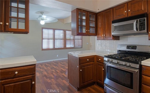 267 E 16th St, Costa Mesa, CA 92627 - kitchen featuring appliances with stainless steel finishes, tile counters, dark wood-style floors, a ceiling fan, and decorative backsplash
