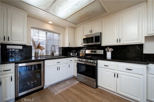 818 Live Oak Pl, Corona, CA 92882 - kitchen with appliances with stainless steel finishes, beverage cooler, white cabinetry, dark countertops, and recessed lighting