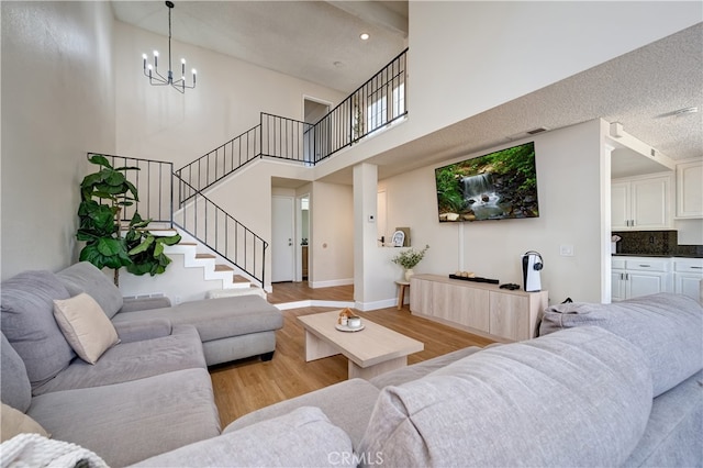 818 Live Oak Pl, Corona, CA 92882 - living area featuring a high ceiling, stairs, a chandelier, light wood-style floors, and a textured ceiling