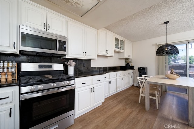 818 Live Oak Pl, Corona, CA 92882 - kitchen with stainless steel appliances, dark countertops, light wood-type flooring, white cabinets, and backsplash