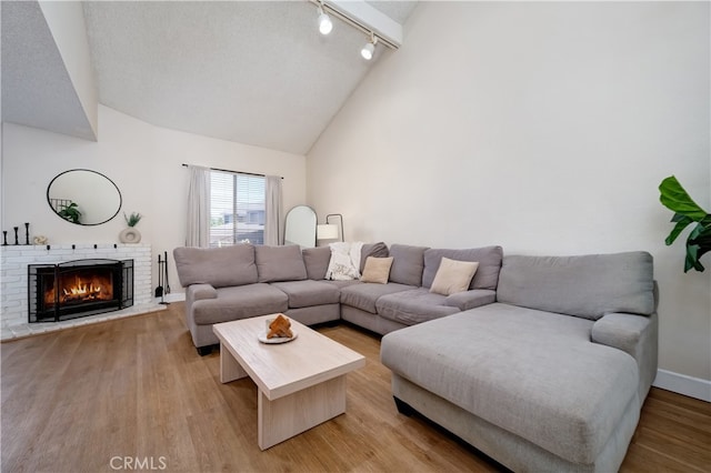 818 Live Oak Pl, Corona, CA 92882 - living room with track lighting, light wood finished floors, a brick fireplace, high vaulted ceiling, and a textured ceiling