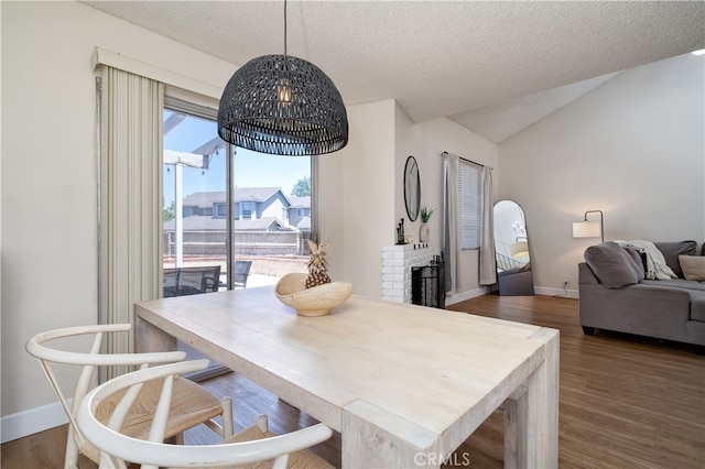 818 Live Oak Pl, Corona, CA 92882 - dining space featuring wood finished floors, a brick fireplace, a textured ceiling, and vaulted ceiling