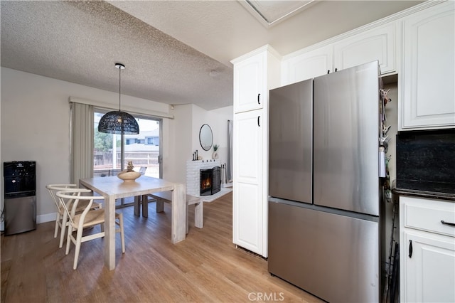 818 Live Oak Pl, Corona, CA 92882 - kitchen with freestanding refrigerator, a textured ceiling, light wood-type flooring, white cabinetry, and a fireplace