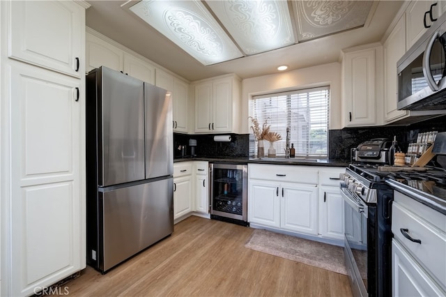 818 Live Oak Pl, Corona, CA 92882 - kitchen with appliances with stainless steel finishes, wine cooler, dark countertops, light wood-style floors, and white cabinets