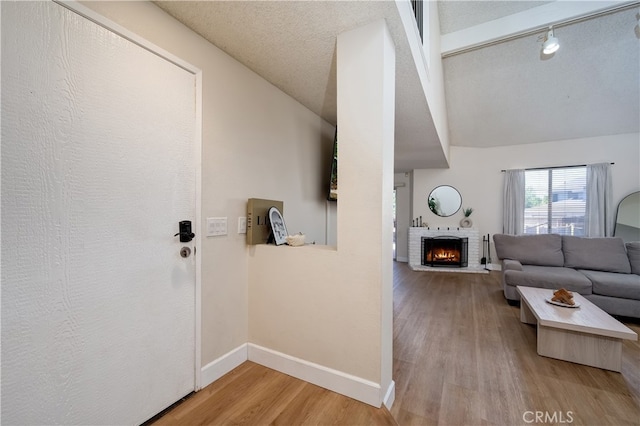 818 Live Oak Pl, Corona, CA 92882 - living room featuring lofted ceiling, wood finished floors, a brick fireplace, and a textured ceiling